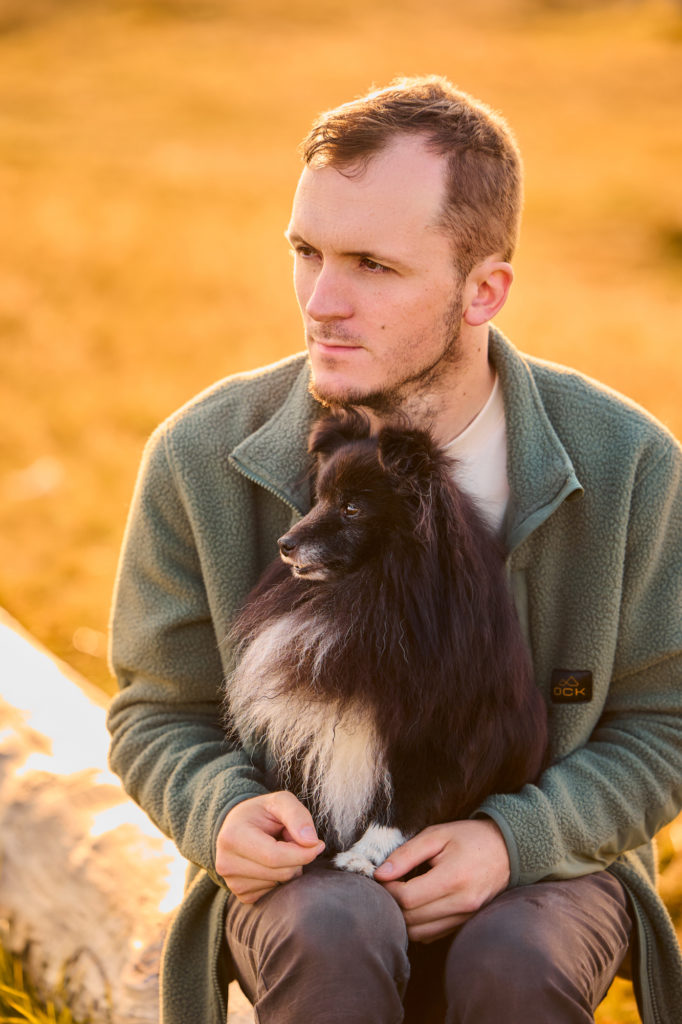 Ein Shetland Sheepdogs mit seinem Hundebesitzer auf dem Herzogenhorn im Schwarzwald bei Sonnenaufgang mit Blick auf den Feldberg