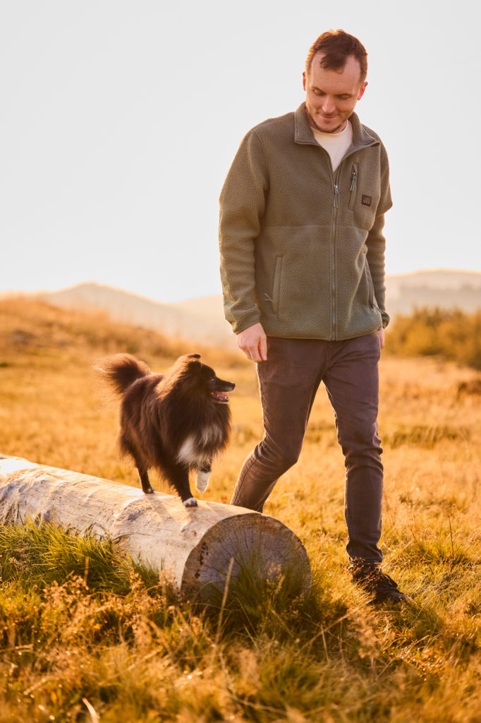 Ein Shetland Sheepdogs mit seinem Hundebesitzer auf dem Herzogenhorn im Schwarzwald bei Sonnenaufgang mit Blick auf den Feldberg