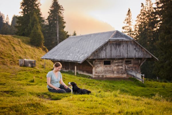 Entlebucher Sennenhund mit Hundebesitzerin bei einem Fotoshooting in Entlebuch in der Schweiz im Sonnenuntergang, professionelles Hunde-Fotoshooting in der Natur