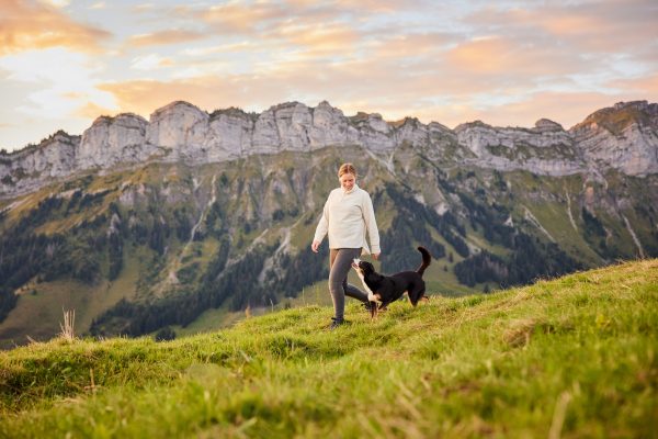 Entlebucher Sennenhund mit Hundebesitzerin bei einem Fotoshooting in Entlebuch in der Schweiz im Sonnenaufgang, professionelles Hunde-Fotoshooting in der Natur