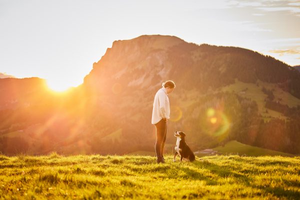 Entlebucher Sennenhund mit Hundebesitzerin bei einem Fotoshooting in Entlebuch in der Schweiz im Sonnenaufgang, professionelles Hunde-Fotoshooting in der Natur